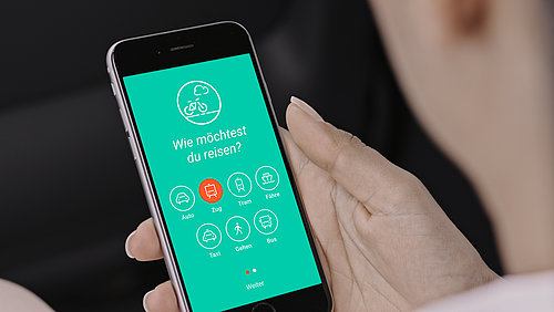 Eine Frauenhand hält ein Handy mit der geöffneten App abilio.